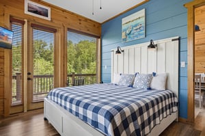 Wake up to forest views streaming through your private balcony doors in this cozy blue and white bedroom retreat.