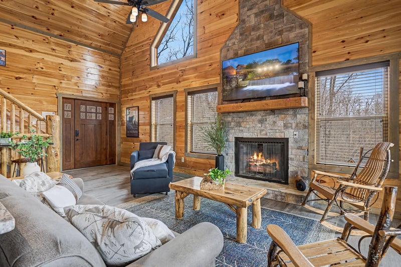 Unwind by your crackling stone fireplace in this warm cabin living room, complete with cozy seating and rustic charm.