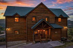 Stunning log cabin with warm lighting glows invitingly against a vibrant sunset sky, set among rolling hills in a peaceful mountain community.