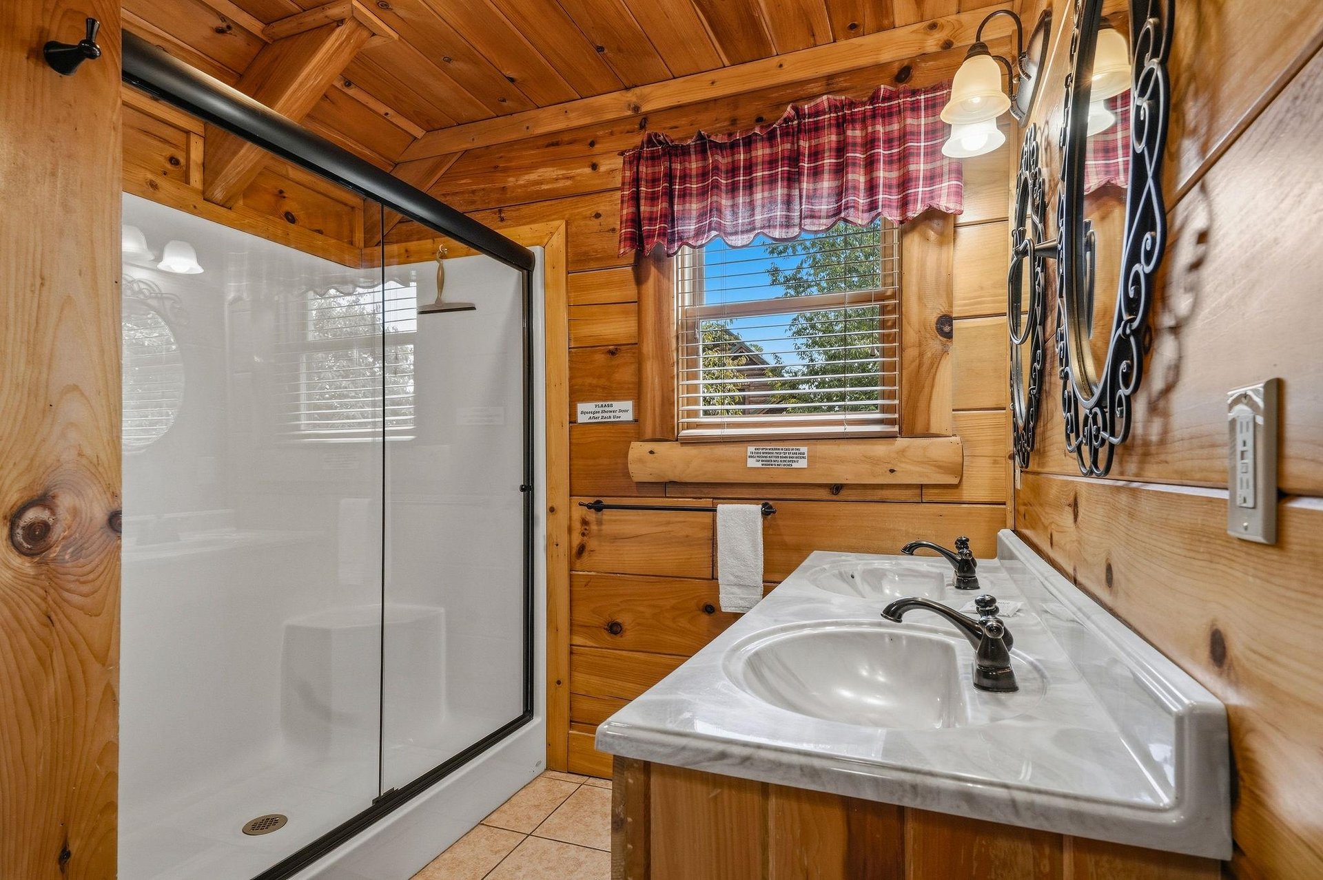 Freshen up in your cozy, cabinstyle bathroom with a walkin shower, warm wood finishes, and natural light streaming through the window.