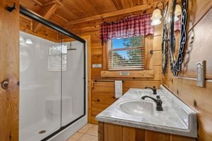 Freshen up in your cozy, cabinstyle bathroom with a walkin shower, warm wood finishes, and natural light streaming through the window.