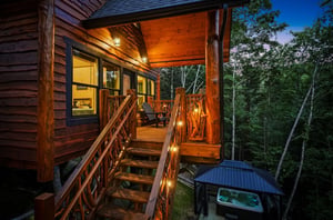 A covered wooden deck nestled among towering trees glows warmly at dusk, offering a peaceful spot to unwind with nature surrounding you.