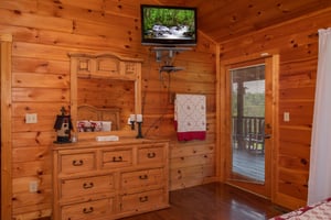 Bedroom with a dresser and mirror, a wallmounted television, and deck access at Cabin Fever, a 4bedroom cabin rental located in Pigeon Forge