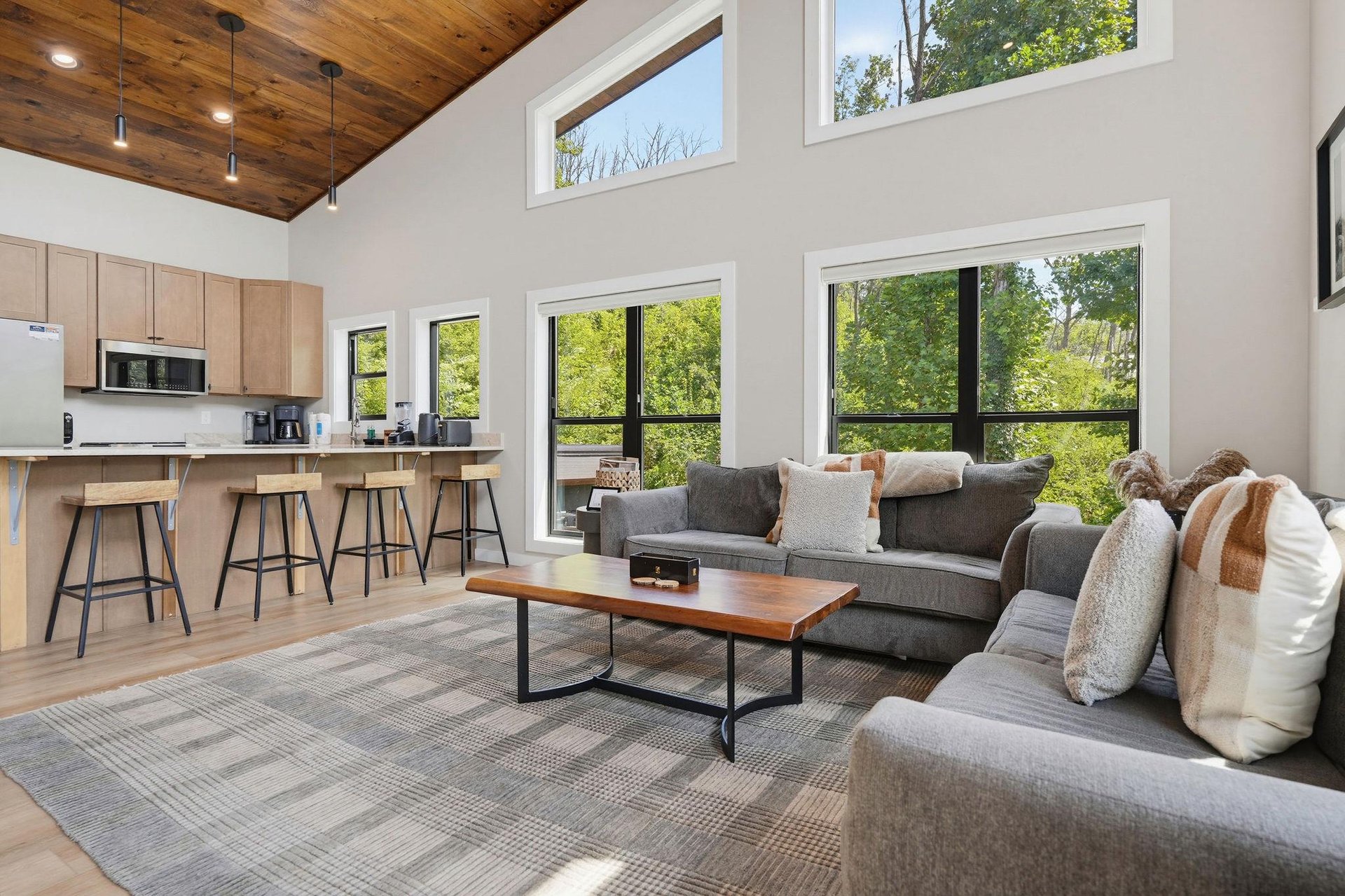 Sink into plush seating beneath soaring vaulted ceilings while natural light pours through floortoceiling windows framing lush greenery. An openconcept layout connects you to the modern kitchen, pe