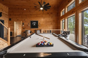 Gather around for a friendly game of pool in this stunning woodpaneled game room, where natural light and mountain views create the perfect backdrop for your vacation fun.