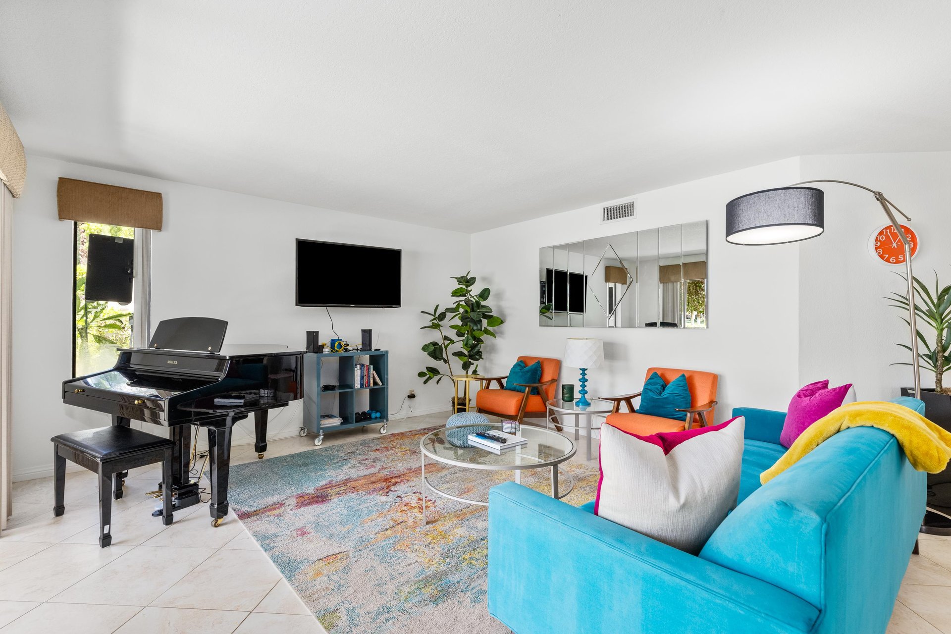 Inviting living room with ample seating, flatscreen TV, piano, and patio access.