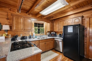 Your rustic cabin kitchen features granite counters, full appliances, and warm wood beams—perfect for cozy mountain meal prep.