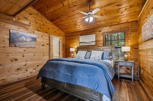 Drift off surrounded by warm wood tones and the gentle hum of your ceiling fan—your cozy cabin retreat awaits for the perfect nights rest.