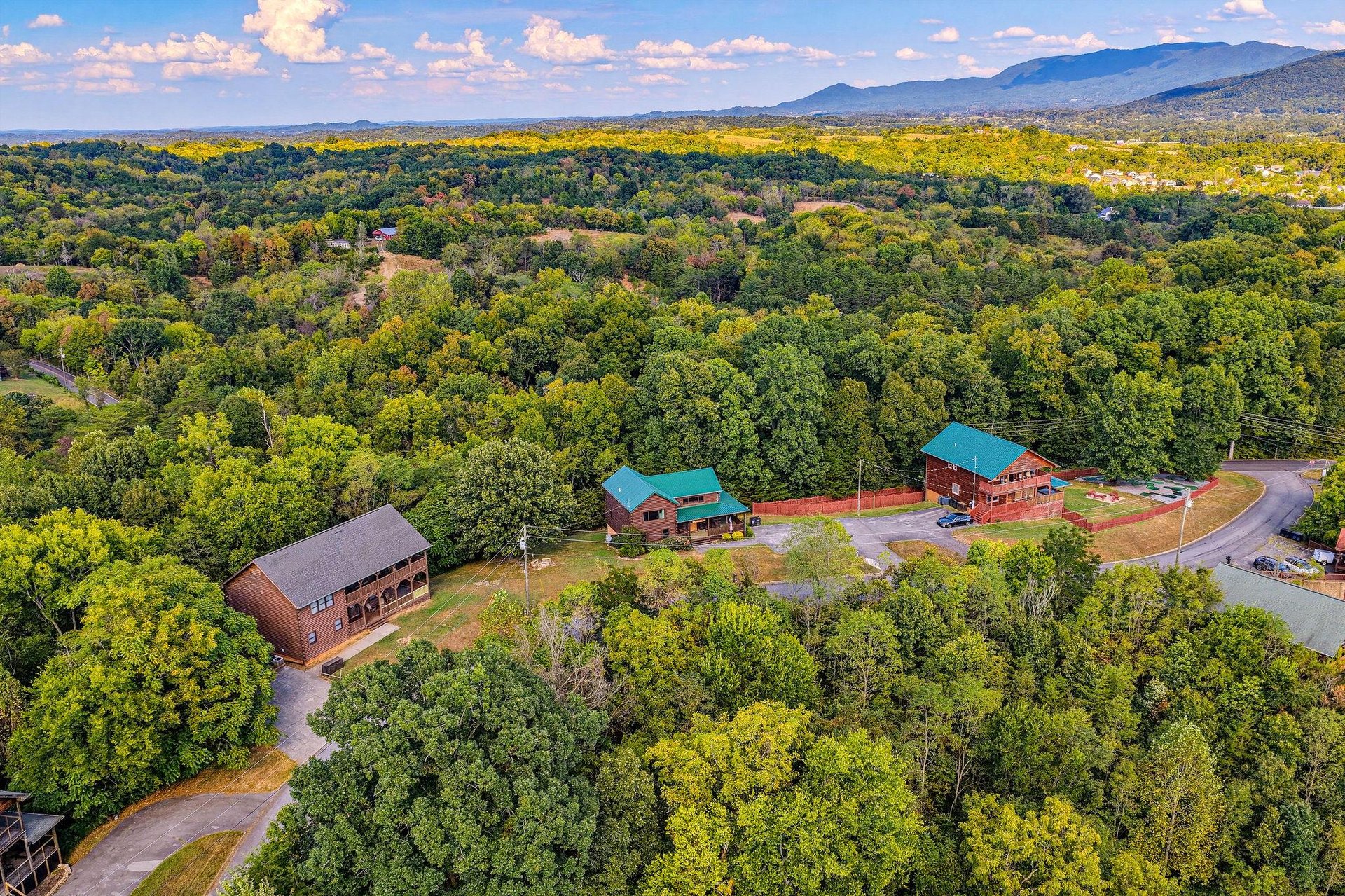 This aerial perspective showcases the property nestled in lush forest, with mountain vistas and natural beauty enveloping the peaceful setting.