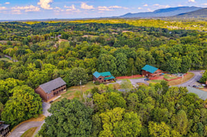 This aerial perspective showcases the property nestled in lush forest, with mountain vistas and natural beauty enveloping the peaceful setting.