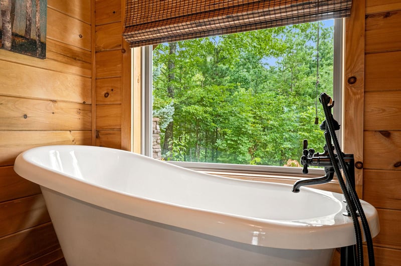 Sink into this inviting soaking tub surrounded by warm wood and a stunning view of lush greenery just beyond the window—your perfect escape.
