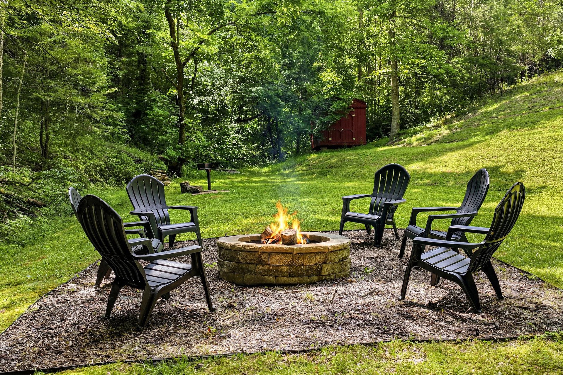 Charming outdoor fire pit area surrounded by lush woodland, perfect for evening gatherings under the stars.
