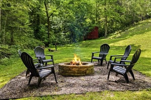 Charming outdoor fire pit area surrounded by lush woodland, perfect for evening gatherings under the stars.