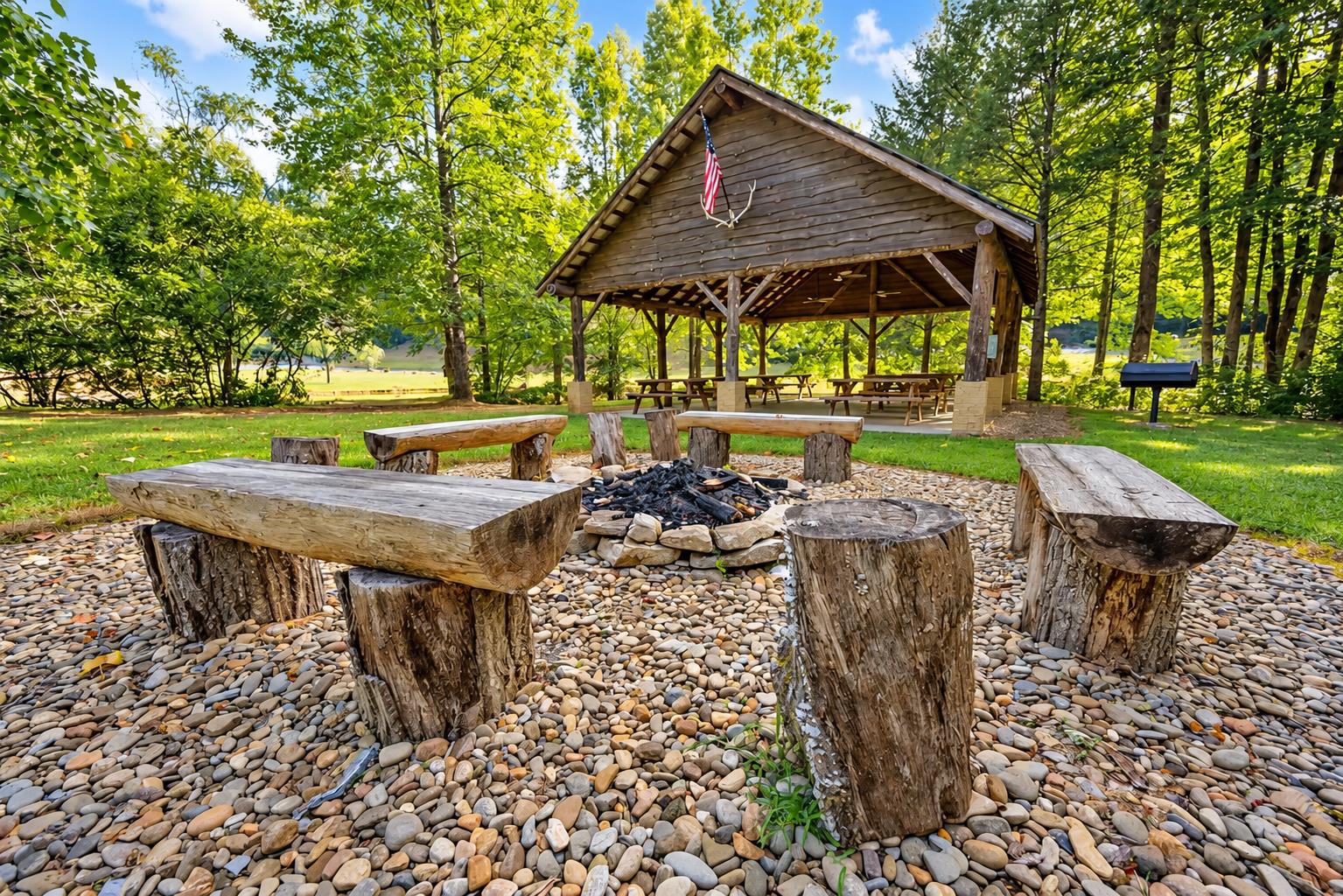 A rustic outdoor pavilion surrounded by vibrant greenery creates the perfect backdrop for your next gathering. A stone fire pit ringed by log benches offers a cozy spot for evening smores and shared 
