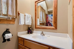 Charming bathroom with rustic wood accents, a welcoming bear companion, and plush towels waiting for your arrival.