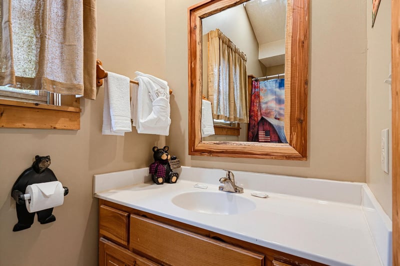Charming bathroom with rustic wood accents, a welcoming bear companion, and plush towels waiting for your arrival.