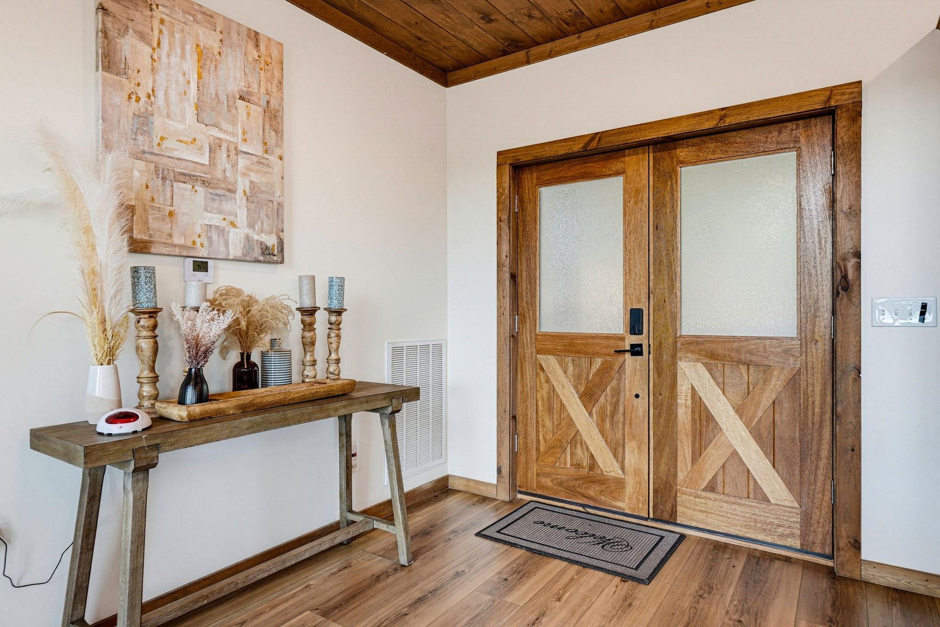 A warm, rustic entryway welcomes you with beautiful barnstyle wood doors and a charming decorative table. Notice the elegant wood ceiling adding cozy character to your arrival.