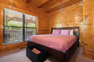 Wake up in a serene cabin bedroom wrapped in warm wood from floor to ceiling. Natural light streams through large windows, inviting you to start your day refreshed and relaxed.