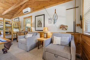 Curl up in your cozy living area framed by warm wood beams and charming nautical décor. Plush seating invites quiet moments, while rustic touches create a welcoming cabin vibe.