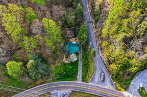 Aerial view of a peaceful property nestled among lush trees with a pristine swimming pool and manicured grounds.