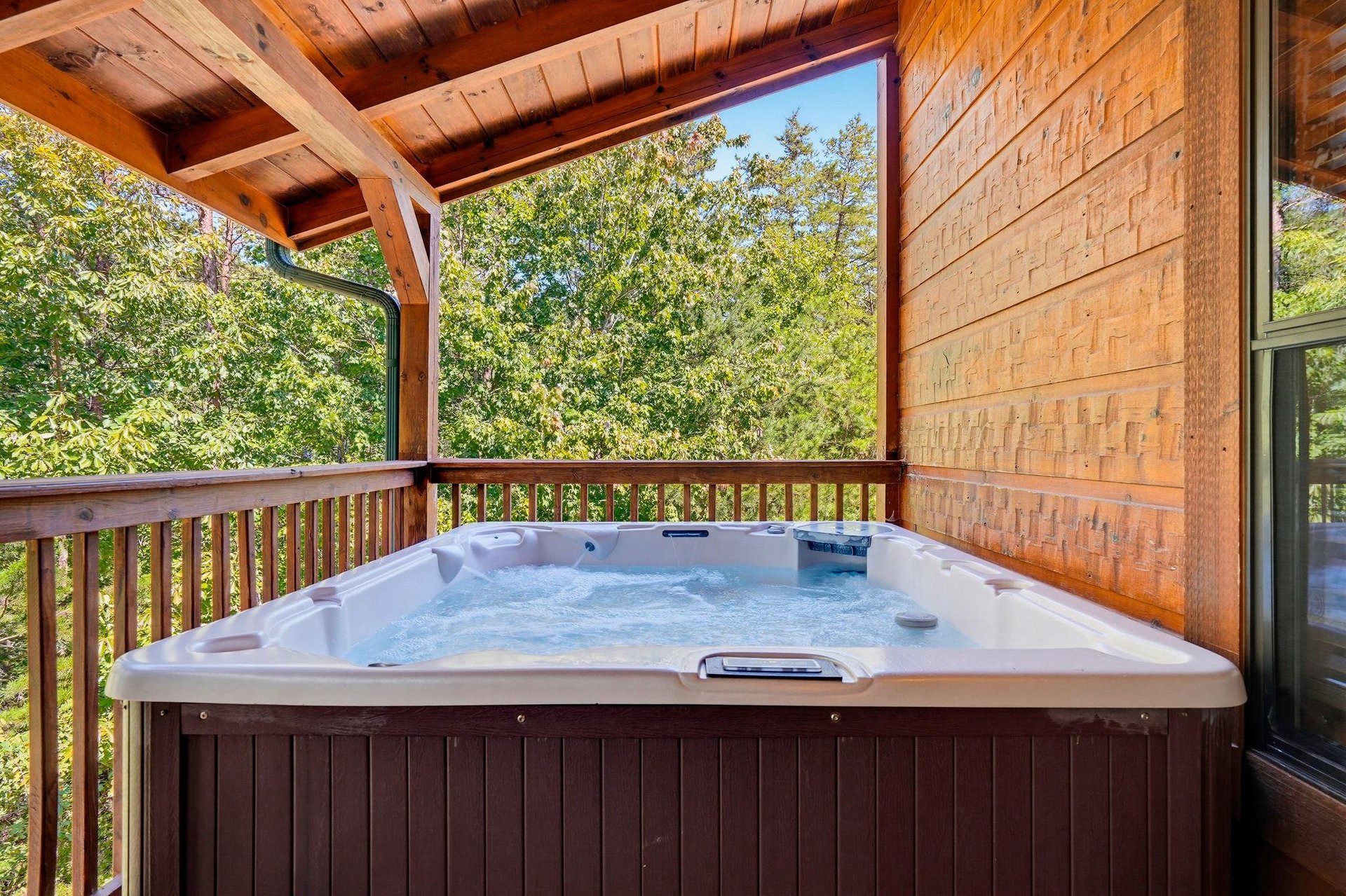 Slip into your private hot tub on the covered deck, surrounded by lush trees and warm wood tones. The perfect spot to unwind under open skies.