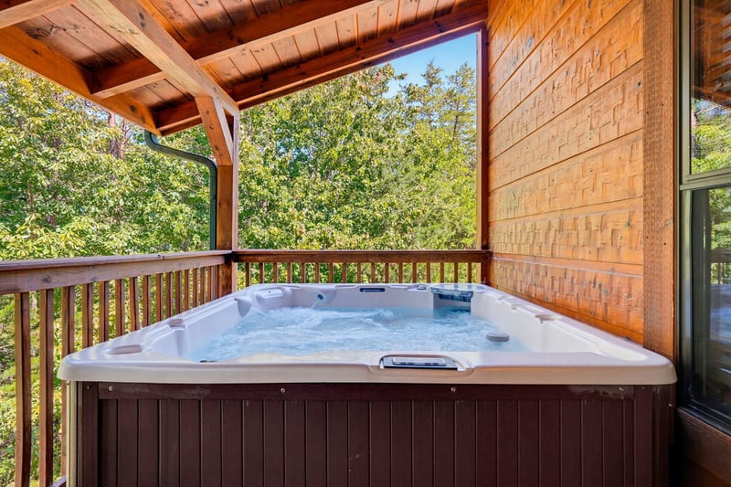 Slip into your private hot tub on the covered deck, surrounded by lush trees and warm wood tones. The perfect spot to unwind under open skies.