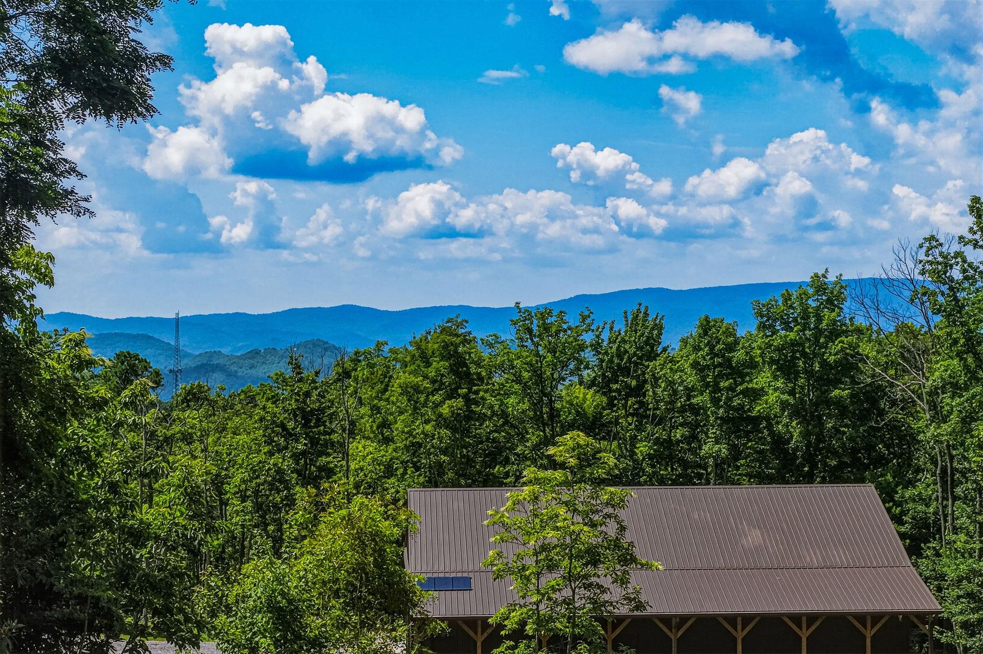 Property set among rolling blue mountains and lush forest, with dramatic cloud formations overhead creating a scenic natural backdrop.