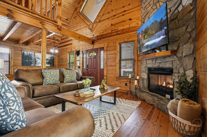 Relax in your cozy living room with rustic wood beams, stone fireplace, and plush seating where warmth meets mountain charm.