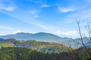 Rolling mountain ranges create a stunning backdrop with layered peaks stretching into the distance under bright blue skies.