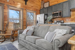 Sink into this plush gray sofa surrounded by warm wood walls and rustic charm, with your kitchen just steps away for cozy meal prep.
