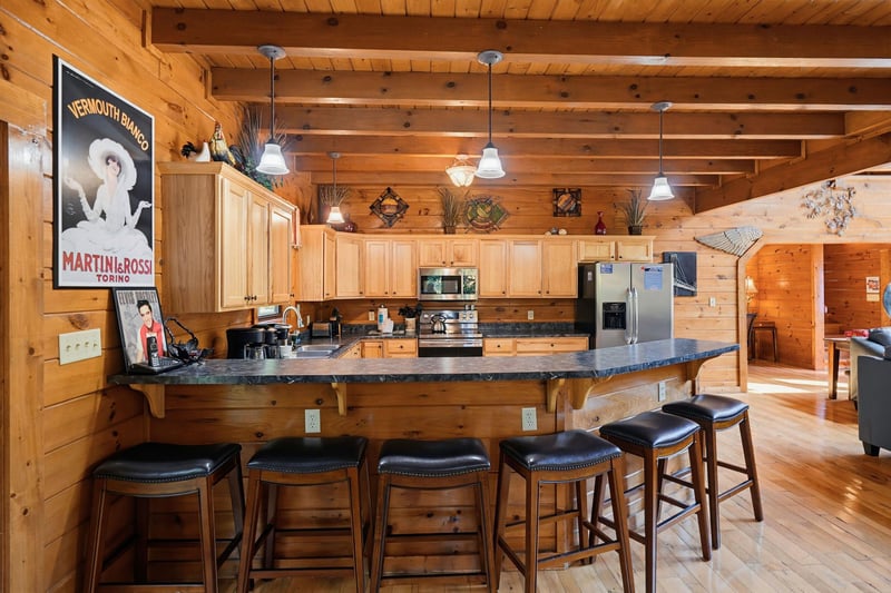 Gather around the spacious kitchen island with breakfast bar seating, where warm wood beams and modern appliances blend rustic charm with convenience for your mountain getaway.