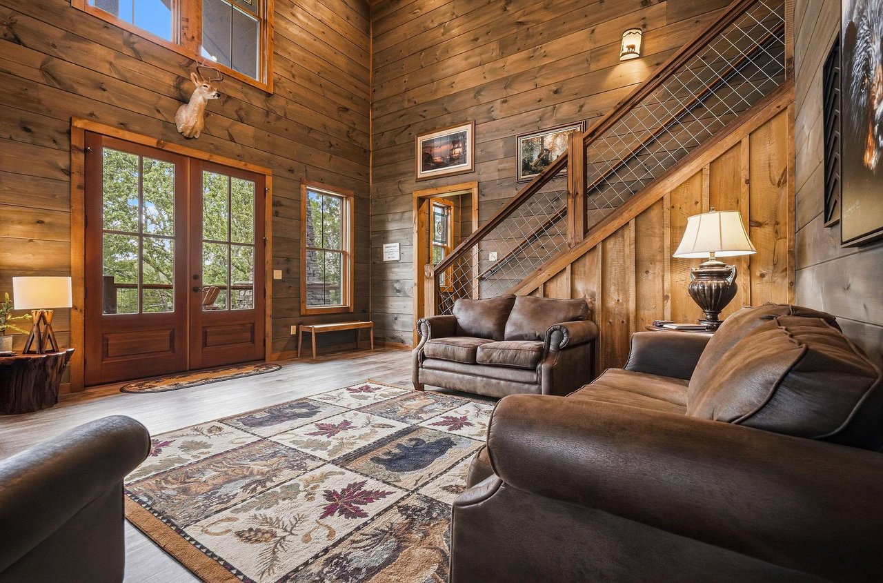 Youll love relaxing in this inviting living room, where soaring woodpaneled ceilings, rich leather sofas, and rustic mountain charm create a warm, welcoming retreat after your adventures.