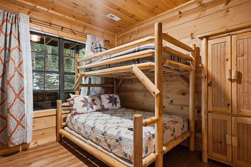 Cozy up in this charming bunk room with rustic log furniture, soft quilted bedding, and a warm pine interior that wraps you in cabin comfort.