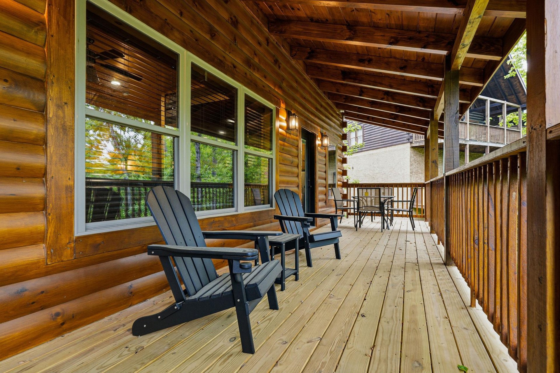 Unwind on your private covered deck with comfortable Adirondack chairs and dining space, surrounded by warm wood beams and peaceful forest views.