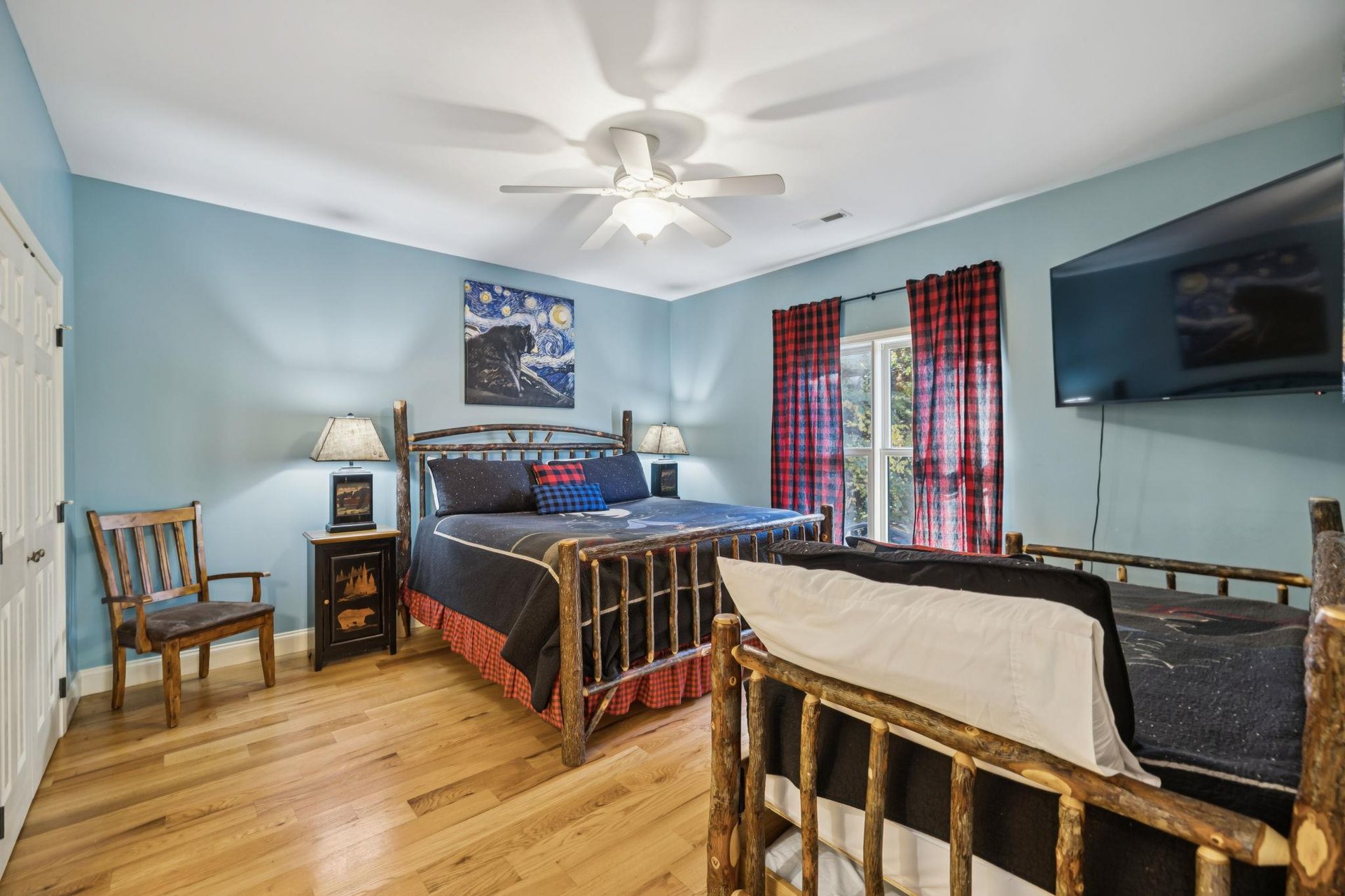 Cozy bedroom with rustic log furniture, soothing blue walls, and thoughtful touches—your peaceful retreat awaits with soft lighting and mountaininspired charm.