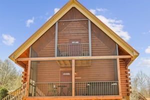 Charming log cabin with bright yellow trim and spacious balconies under a brilliant blue sky.