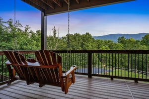 Sink into the porch swing and let your gaze drift across forested hills and distant mountain ridges—your peaceful retreat above the treetops awaits.