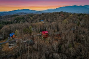 Stunning mountain cabin retreat nestled among rolling hills and forests, with breathtaking sunset views over the surrounding landscape.