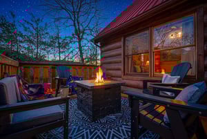 Cozy up beside your private fire table under starlit skies, wrapped in soft blankets while the cabin glows warmly behind you.