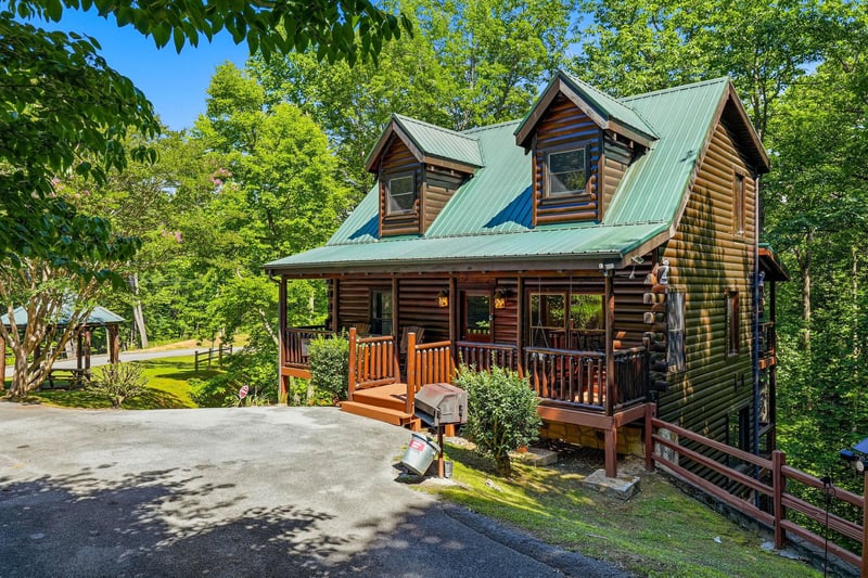 This charming log cabin is nestled in lush greenery, offering a peaceful mountain retreat with convenient parking and a welcoming front porch perfect for unwinding.