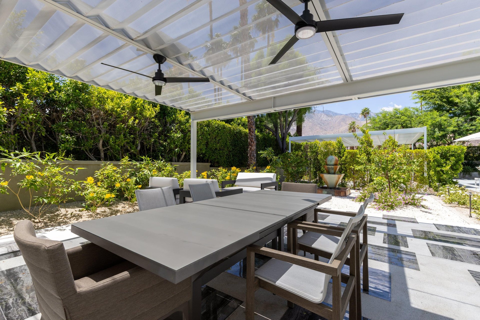 Outdoor dining area under pergola with fan, table, and seating for 6 guests.
