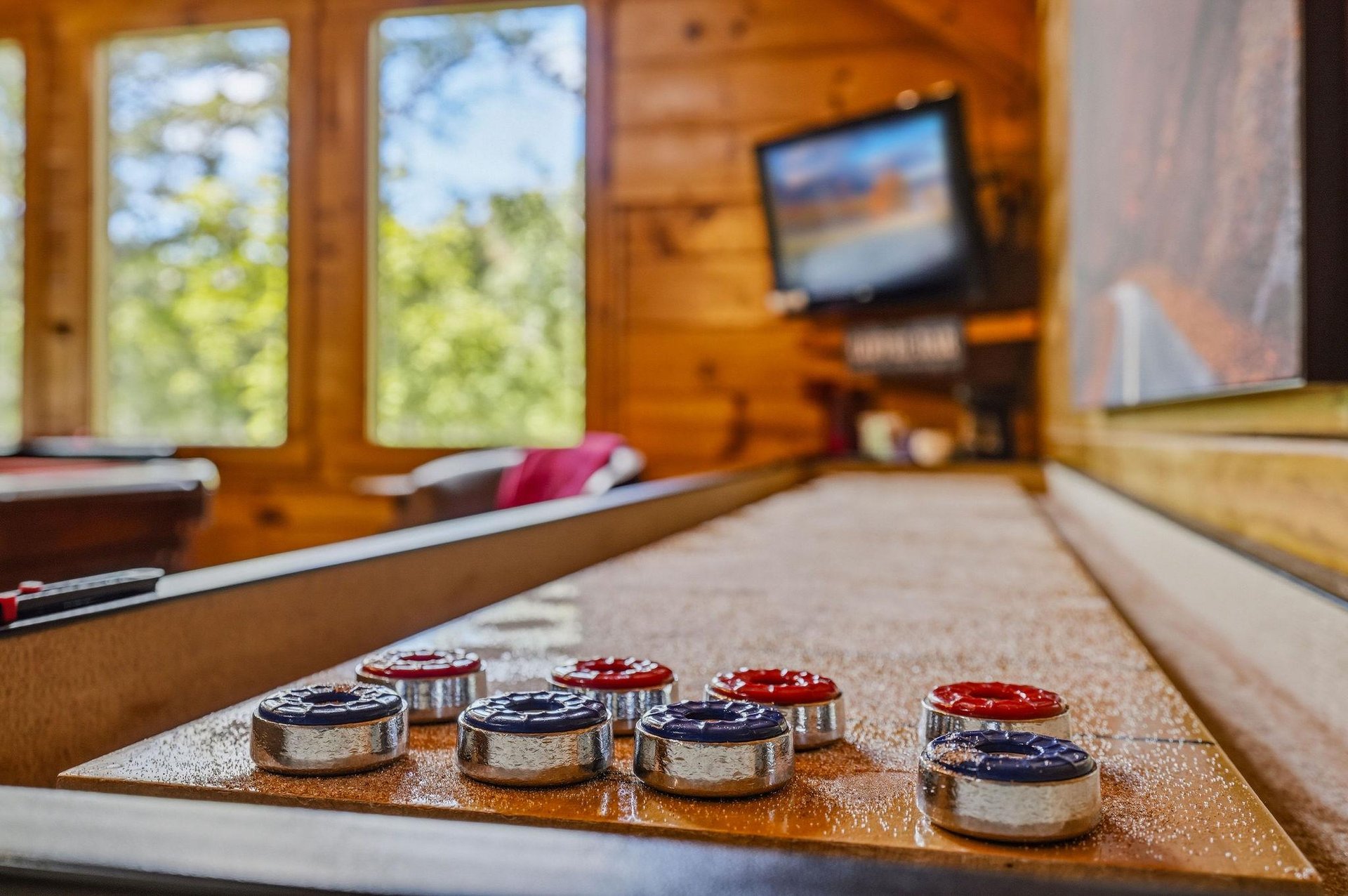 Gather around for a friendly game in this cozy cabin retreat, where rustic wood walls, natural light, and classic entertainment set the scene for memorable moments with family and friends.