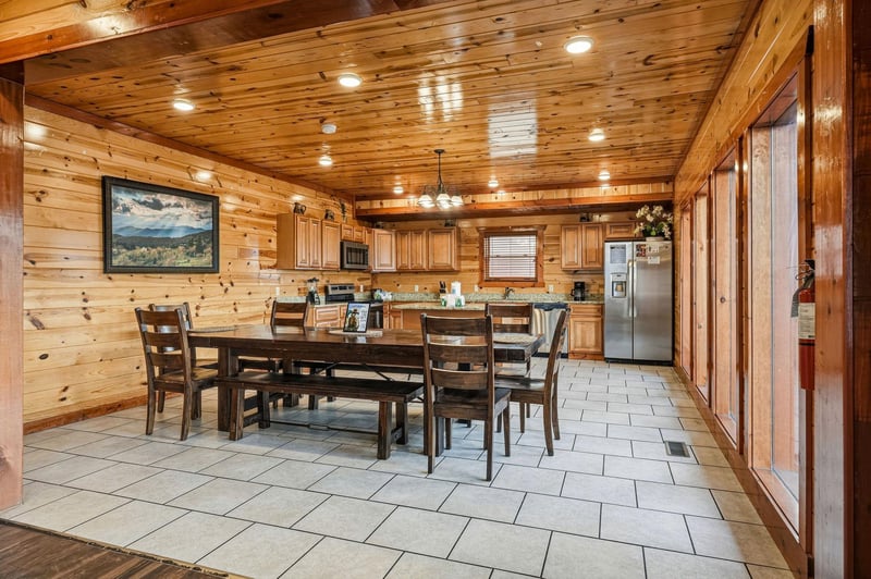 Your spacious cabin kitchen invites family meals with rustic wood beams overhead and a generous dining table perfect for morning coffee together.