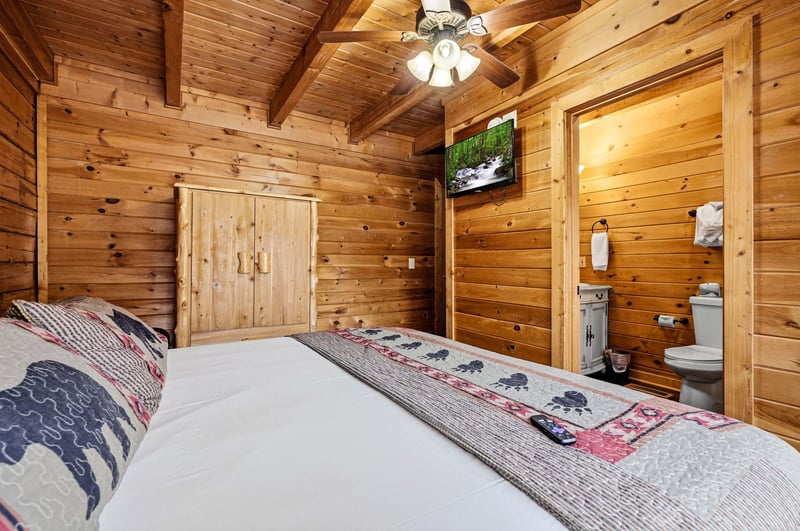 Sink into the rustic charm of this cozy log cabin bedroom, where warm wood surrounds you and your private bathroom awaits.