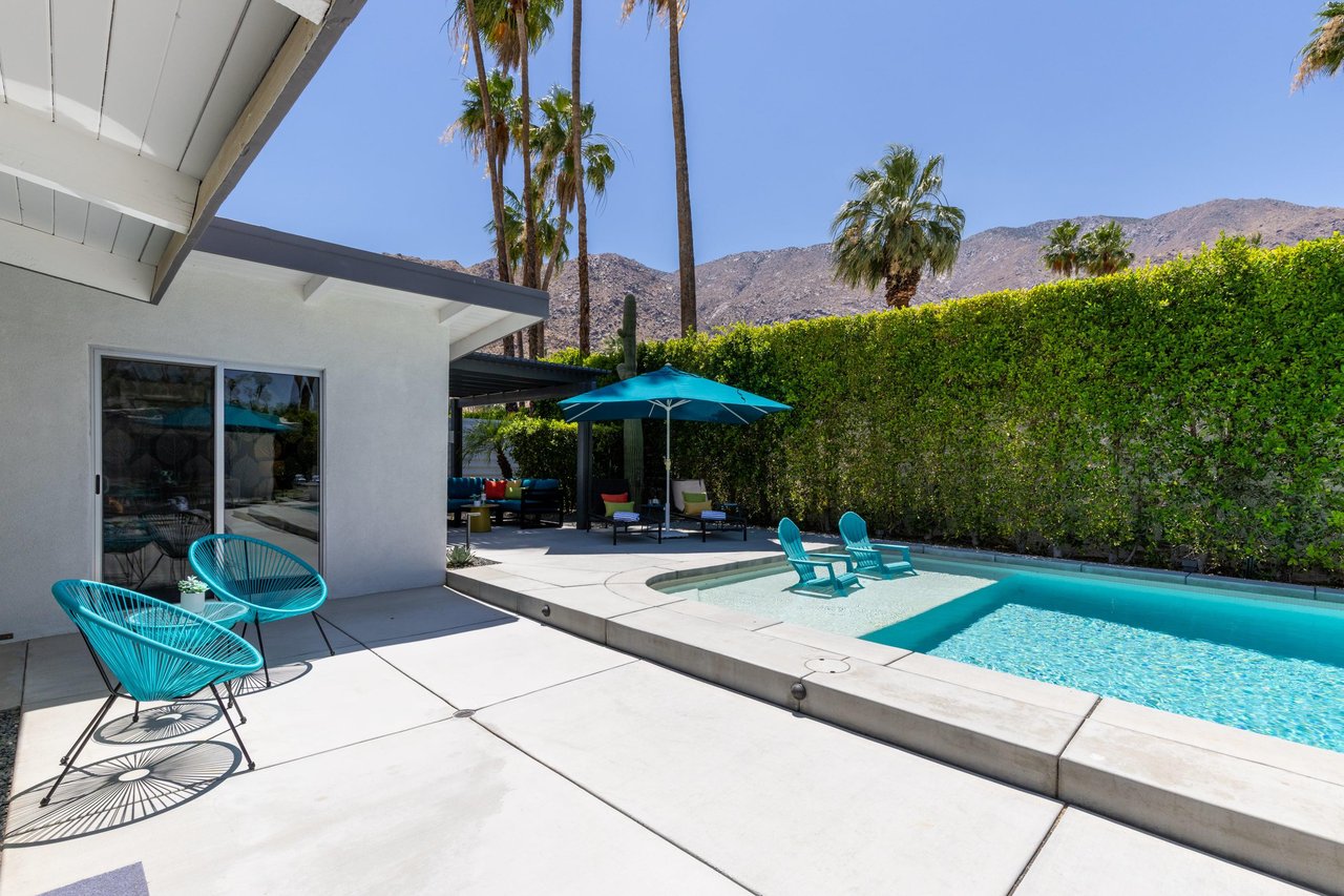View of pergola with shaded outdoor seating and shallow end in pool.