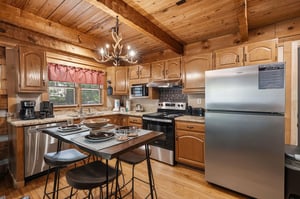 Warm wood beams and golden cabinetry frame your fully equipped kitchen, where modern appliances and granite countertops make meal prep effortless. The island seating invites casual dining under rustic