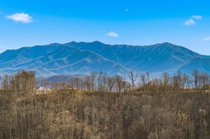 Majestic mountain ranges stretch across the horizon, creating a stunning backdrop for this scenic location with rolling hills and natural beauty.