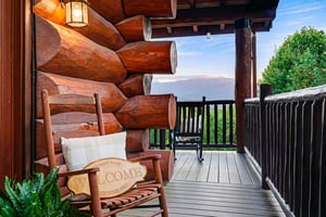 Picture yourself on this private covered deck, where a rustic log cabin meets serene mountain views. A welcoming rocking chair invites quiet moments as you take in the natural beauty surrounding your 