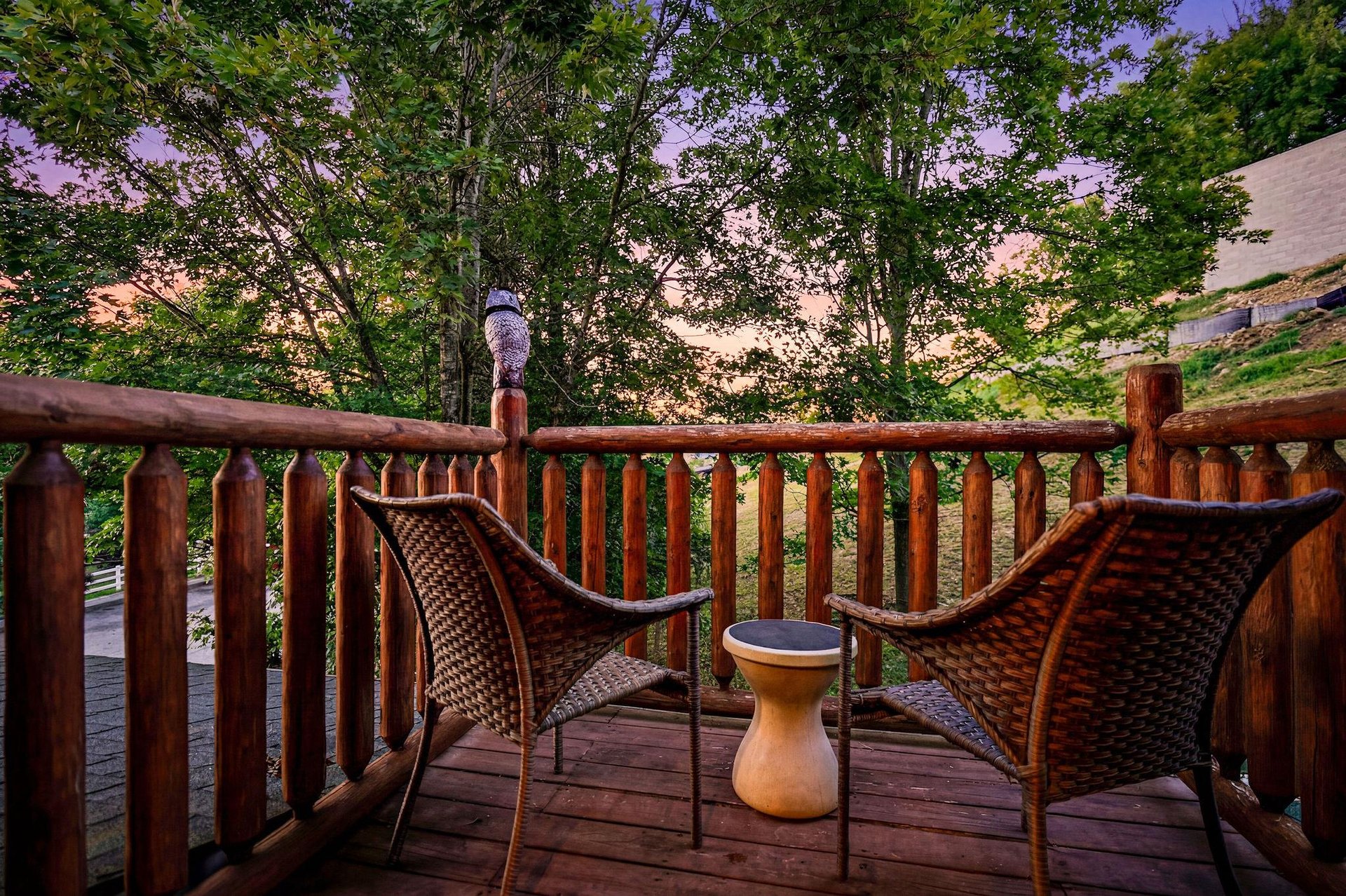 A tranquil deck area framed by mature trees and soft twilight colors, offering a peaceful retreat in a wooded setting near the property.