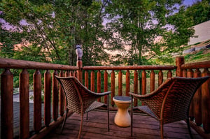A tranquil deck area framed by mature trees and soft twilight colors, offering a peaceful retreat in a wooded setting near the property.